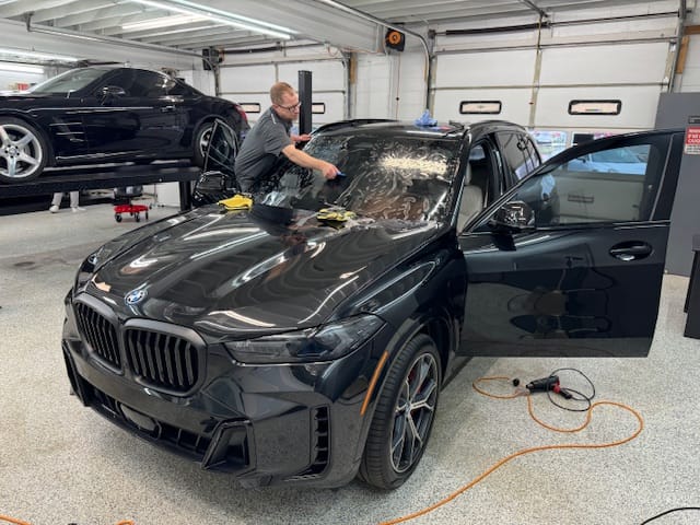 Black BMW Suv getting windshield protective film installed