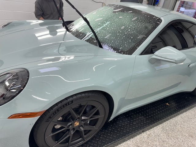 Grey Porsche getting windshield protective film installed